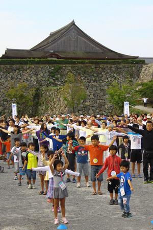 篠山城跡に集まる沢山の老若男女が、体操をしている写真