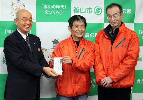 市長が大上 裕さん、市野 良行さんと一緒に寄付袋を持って笑顔で記念写真