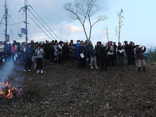 焚火をしながら権現山初日を迎える会に参加した市民らが朝日の写真を撮影しようとおのおのカメラを構えている写真