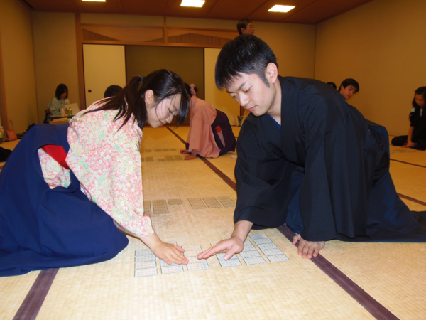 岸田 諭名人が袴姿の女性とかるた協議をしている写真