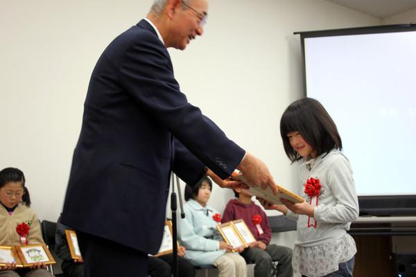 市長が松山 はるか（まつやま はるか）さんに額に入った賞状を渡している写真
