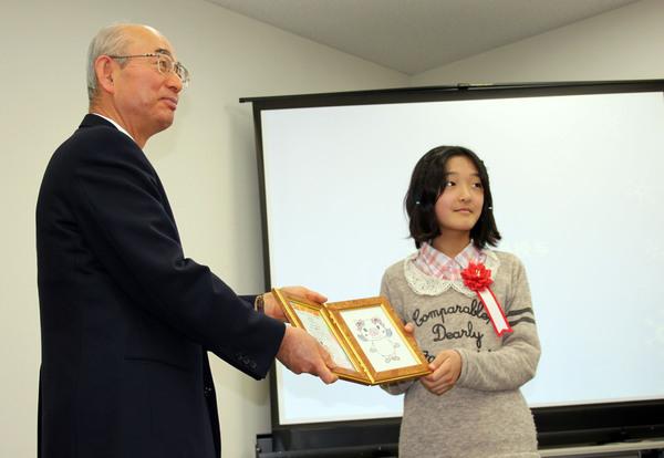 市長が森 優希乃（もり ゆきの）さんに額に入った賞状を渡している写真