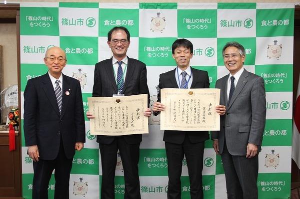 表彰状を持つ小谷先生と依田先生、両端に立つ市長と男性の写真