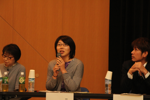 片平 深雪さんがマイクを両手で持ち発表している横で大内 正博さんが右の方向を見ている写真