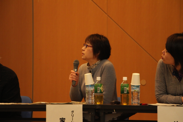 右上の方向を向き、マイクで説明している家澤 美智代さんの写真