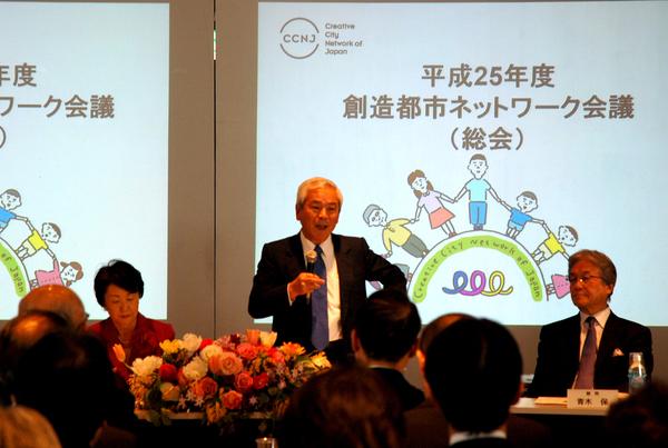 壁面には「平成に25年創造都市ネットワーク会議」と書かれており、青柳文化庁長官がマイクを持って話をしている様子の写真