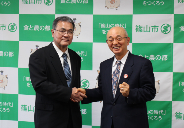 金沢 英雄会長と握手をして笑顔で写っている市長の写真