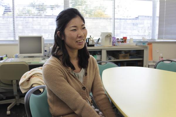 布施 未恵子さんが丸テーブルの椅子に腰かけ、笑顔で写っている写真