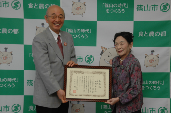 額入りの表彰状を持つ井関 弘子さんと、市長の写真