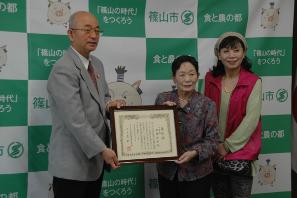 女性と額入りの表彰状を持つ市長と、井関 弘子さんの写真