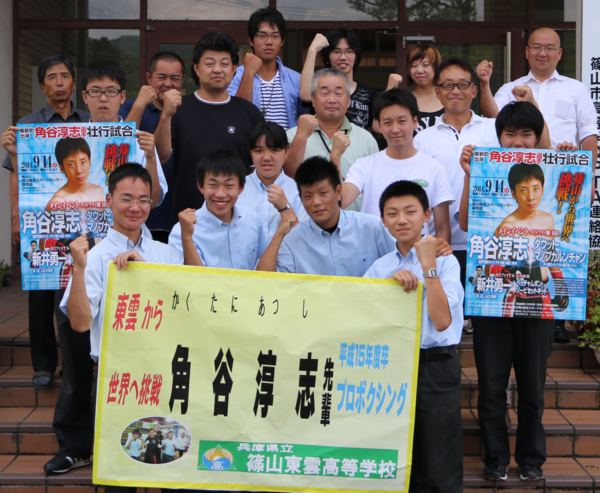 角谷 淳志選手の横断幕、ポスターを持ち、笑顔でガッツポーズをしている応援団の方々の写真