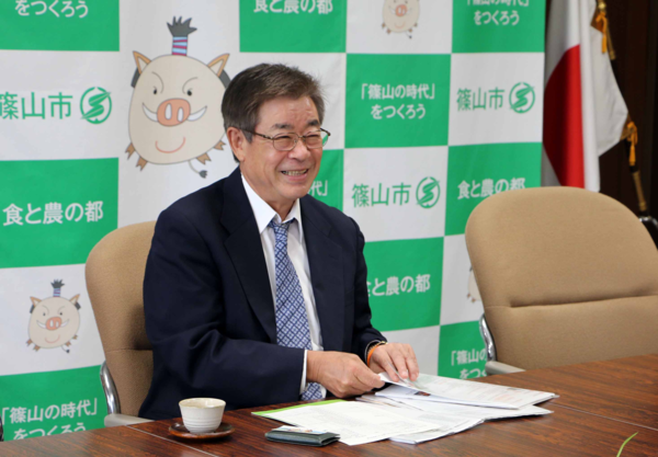 布亀株式会社の方が机に置いてある資料を持って微笑んでいる写真