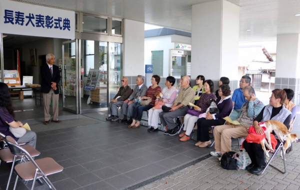 長寿犬表彰式に犬や参加された飼い主が座られていて、獣医師会長が話をしている写真