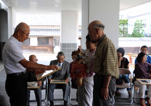 飼い主の男性と長寿犬を抱いた女性に市長が表彰している写真 拡大画像