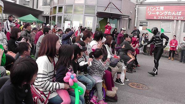 会場にはたくさんの親子が椅子に座り、前の席では戦隊ヒーローがお客さんとふれあっている写真