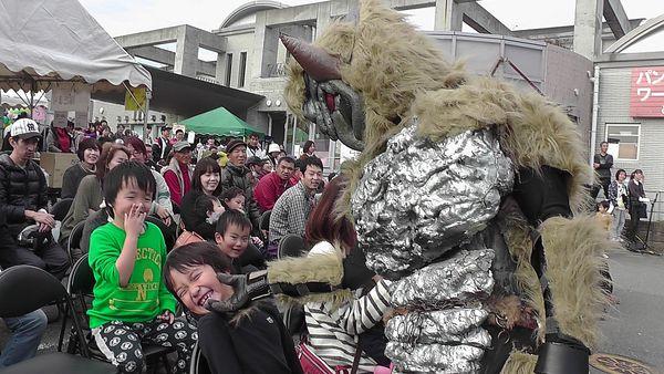 戦隊ヒーローのショウを見に来た子供達が、鬼のような恰好をした悪役に顔をさわられて笑っている写真