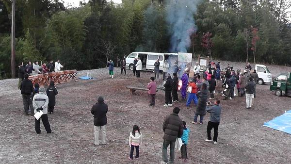 焚き火が炊かれている広場で太鼓の演奏を見ている人々の写真