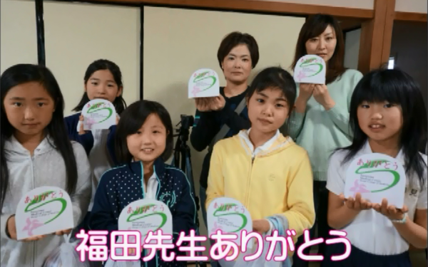 女の子5人と女性2人が「ありがとう」と書かれたメッセージを手に持って写っている写真