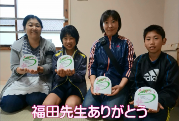 親子2組が「ありがとう」のメッセージカードを持って正座をして写っている写真