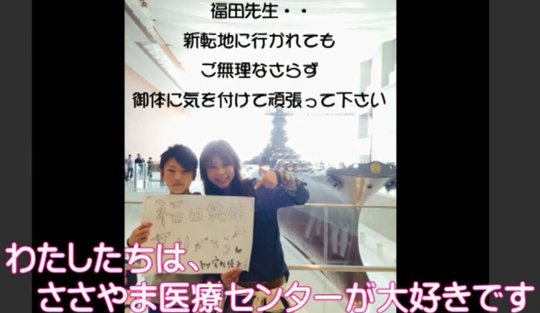 親子が画用紙に書かれた手作りのメッセージプレートを手に持ち笑顔で写っている写真