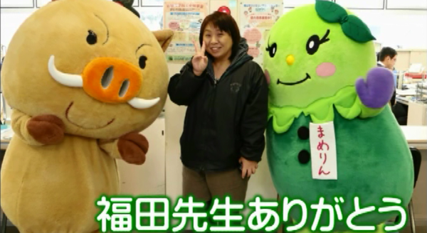 篠山市のマスコット人形と一緒に女性がピースをして笑顔で写っている写真