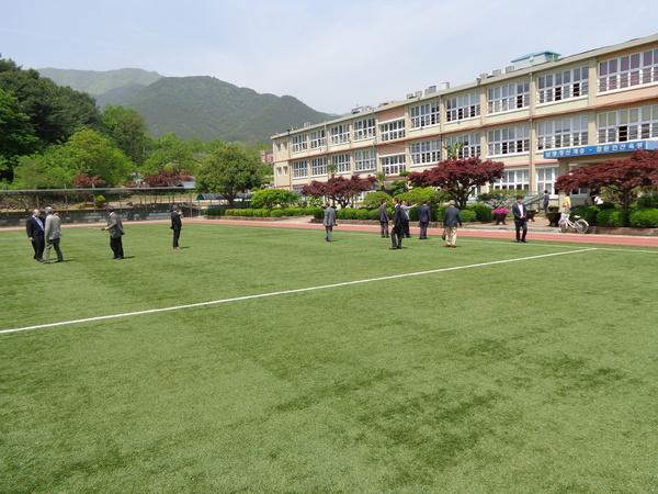 山徳中学校を訪問した篠山市訪問団がグランドの人工芝の上を歩いている写真
