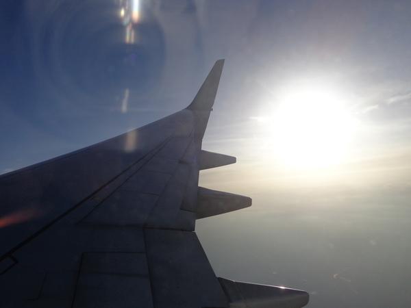 飛行機の翼と太陽の光が飛行機の窓から撮影されている写真
