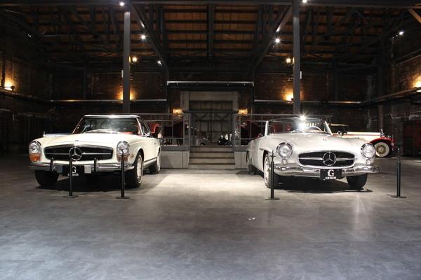 白い2台のクラシックカーがライトに照らされて展示されている写真