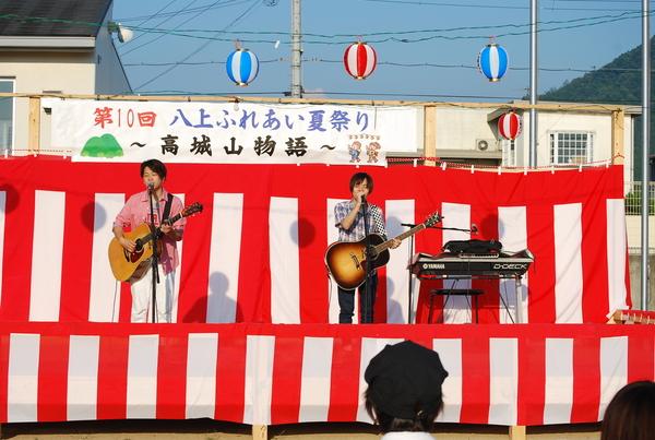 八上ふれあい夏祭りのステージで男性2名がギターをもち歌っている写真