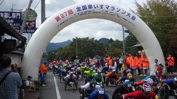 スタート地点から一斉に車いすランナーたちが勢いよく走行している様子の写真