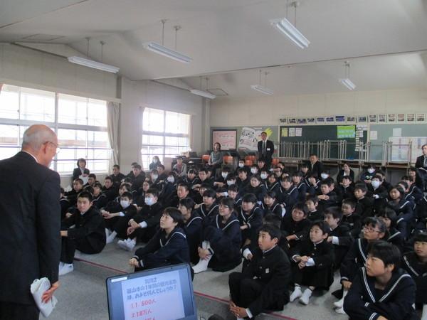 教室の中で生徒たちが体育座りをして市長の話に耳を傾けている写真