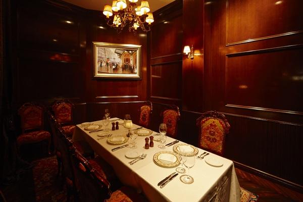 一台のテーブルの上に皿やフォークが置いてあり、奥の壁には絵が飾ってある写真