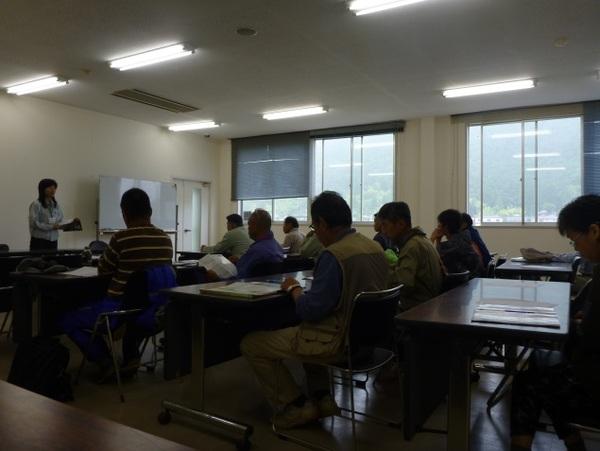 10名ほどの人たちが机に座り、講師の女性から話を聞いている写真