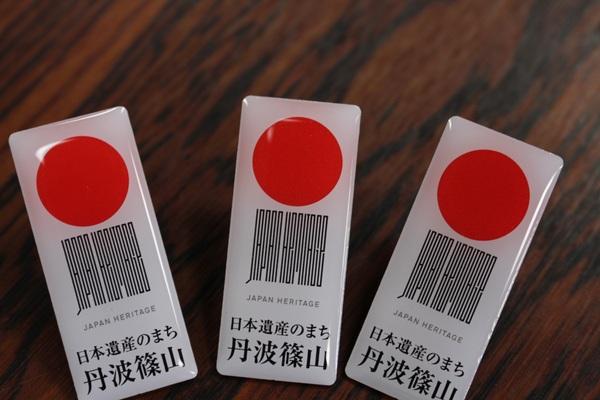 「日本遺産のまち丹波篠山」と書かれたピンバッチが3個テーブルに置いている写真