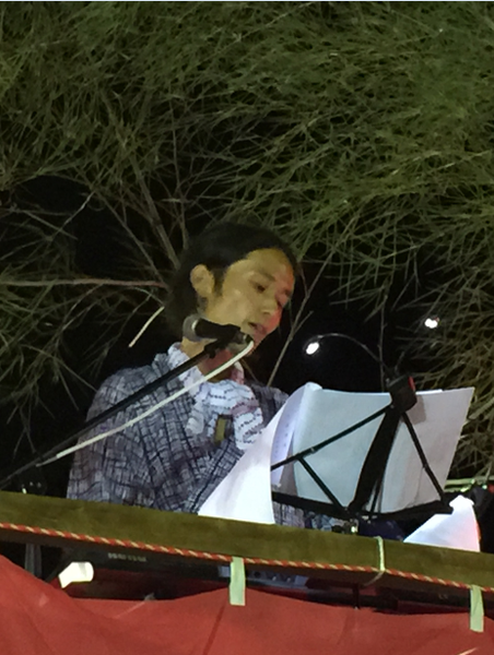 高木さんが楽譜を見ながら、スタンドマイクで歌っている写真