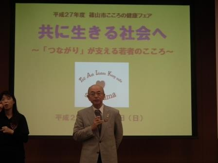 スクリーンの前で市長が挨拶をしている写真