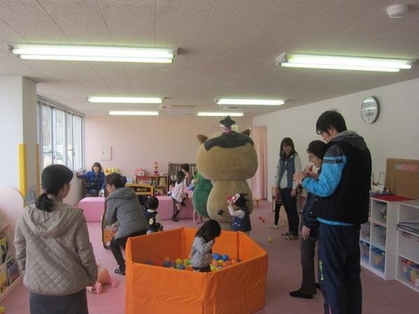 絵本や遊具などが沢山あるプレイルームでボール遊びなど思い思いに遊んでいる子供たちを見守っている大人たちの写真