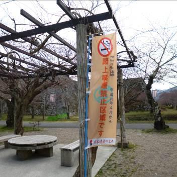 木で出来たテーブルとイスが置かれている休憩場所に路上喫煙禁止区域の旗が立っている写真