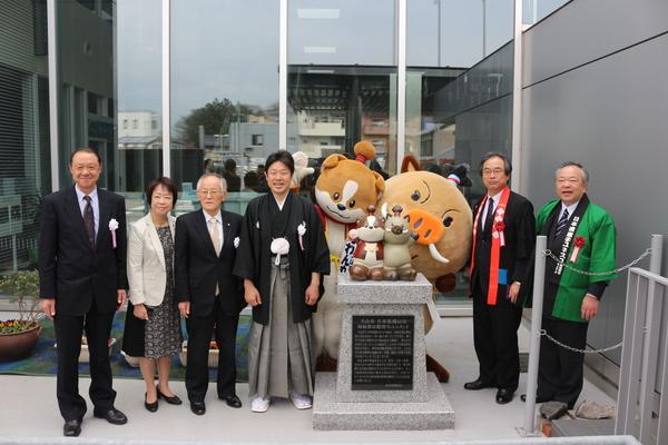 正面玄関前のオブジェの前でゆるキャラ「わん丸君」、「まるいの」も一緒に記念撮影の写真