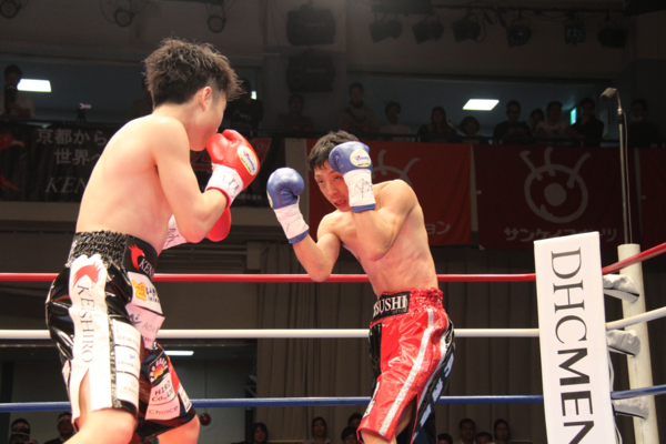 角谷 淳志選手とチャンピオン拳四朗（けんしろう）選手がお互いの攻撃を構えている写真