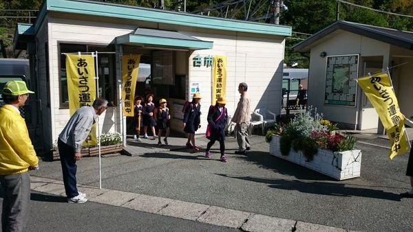 電車から降りてきた小学生とあいさつ運動をする保護者の写真