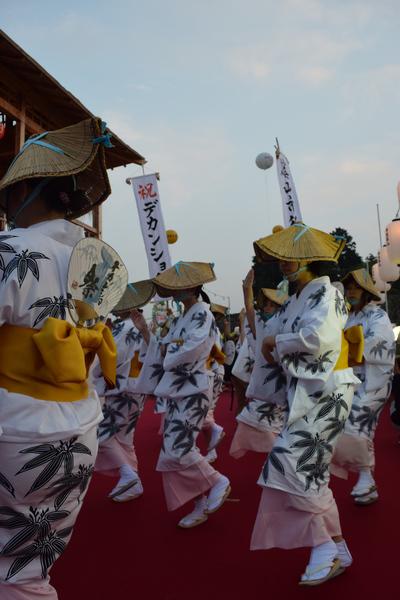 白地に緑の花が描かれた浴衣の黄色の帯にうちわをさして踊っている市役所の方々を横からうつした写真