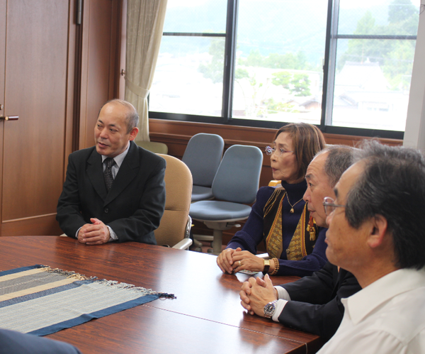 男性3人と女性1人が座って話を聞いている写真
