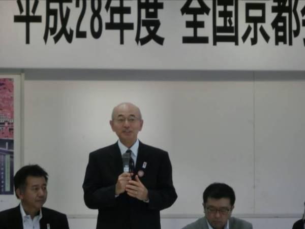 黒いスーツを着た市長がマイクをもって話している写真