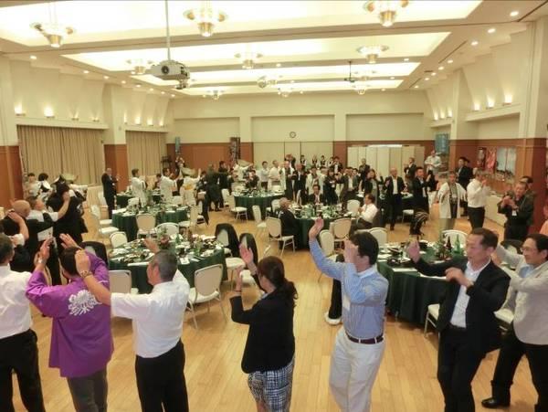 食事会場で参加者30名ほどが輪になって盆踊りを踊っている写真