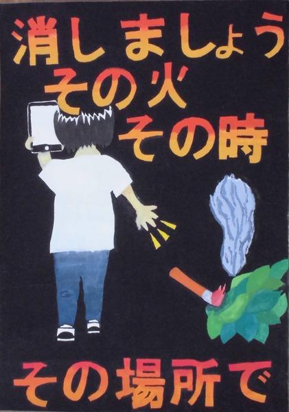 後姿の男性が煙草を草の上にポイ捨てしている絵が描かれていて、消しましょう、その火その時その場所でと文字が書いてあるポスターの写真