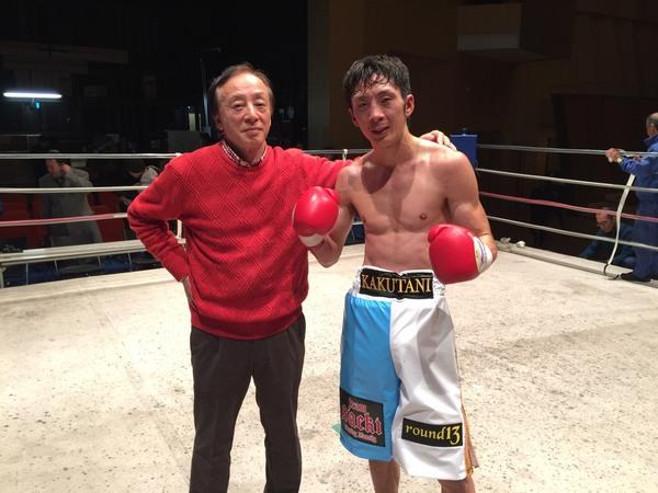 赤いセーターの男性と角谷選手がリンクの上で一緒に映っている写真