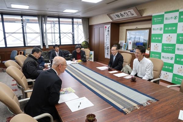 篠山市民ランナーの山下 八寿男さんと西口 昌宏さんが市長と話をしている様子を書記している人々の写真