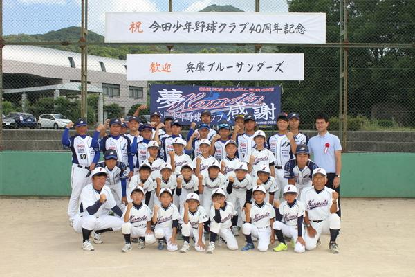 野球のユニホームを着た今田少年野球クラブ部員の子供たちと監督が右腕を挙げてガッツポーズをとっている集合写真