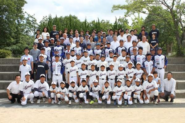 野球のユニホームを着た今田少年野球クラブ部員の子供たちと監督、保護者や指導者、OBや地域の方々の集合写真
